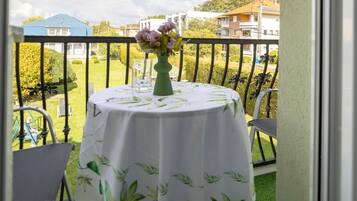 A balcony with a round table, chairs, and a vase of flowers.