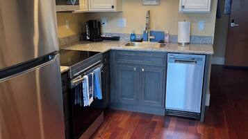A kitchen with white cabinets, stainless steel appliances, a microwave, a dishwasher, and a granite countertop.