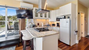 A modern kitchen with a large island, white cabinetry, and a view of the outdoors. - Three Arch Inn (Tillamook)
