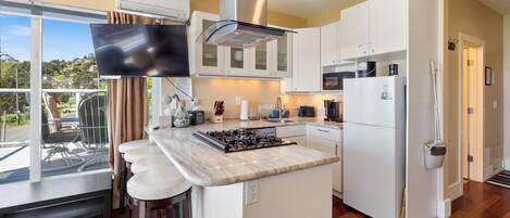 A modern kitchen with a large island, white cabinetry, and a view of the outdoors.