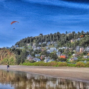 A coastal scene with a beach, cliffs, and a hillside with houses.