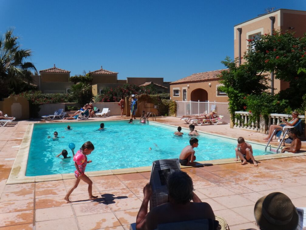 Ein Poolbereich mit mehreren Pools, Liegestühlen und einem Gebäude mit einem Kachel­dach.