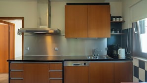 Een moderne keuken met houten kastjes, een roestvrijstalen afzuigkap, een spoelbak en een koffiezetapparaat.