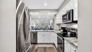 A modern kitchen with stainless steel appliances, white cabinetry, and a view to the outdoors. - 463 Captains Walk is a gorgeous villa with breathtaking views of the ocean. (Hilton Head)