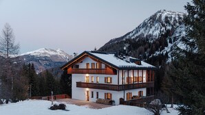 A two-story chalet with a balcony, surrounded by snow-covered mountains and trees. - Piz Boe' with private bio sauna (Livinallongo del col di lana)
