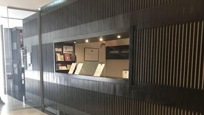 Un comptoir d’accueil au design moderne, avec un revêtement en bois foncé et des lambris verticaux. On peut y voir des certificats encadrés et un tableau affichant le menu.
