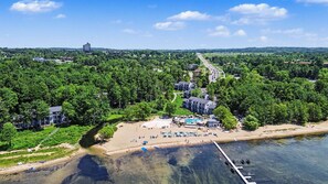 An aerial view of a coastal resort with a swimming pool, beach, and dock. - 🏖️ Gorgeous Chic Beach Front Condo ➠ 5593 (Williamsburg)