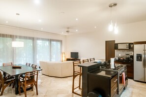 Een moderne keuken met een centraal eiland, een eetgedeelte met een tafel en stoelen, en een zithoek met een bank.
