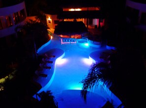 Relax by the pool surrounded by palm trees and a modern dining area.