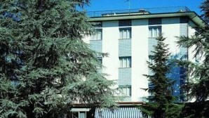 A multi-story building with a white facade and a green roof. There is a sign with the text "SENIO" at the entrance. - Hotel Senio (Riolo Terme)