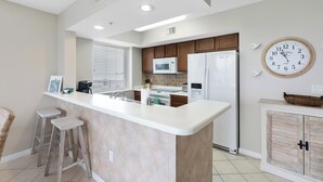 A modern kitchen with a central island, built-in appliances, and a large wall clock.