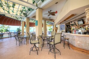 Un espace bar avec un comptoir, des chaises et un ventilateur de plafond.