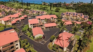A resort with multiple buildings, a parking area, and a view of the ocean. - Aloha Condos, Kona Coast Resort, Condo 1-304, Ocean View (Kailua Kona)