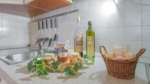 Ett kök med vita kakelplattor, en diskho i rostfritt stål och en upphängd hylla för köksredskap.