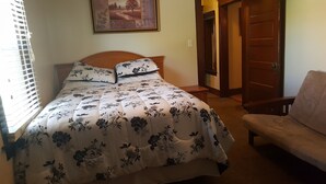 A bedroom with a bed, a chair, and a door.