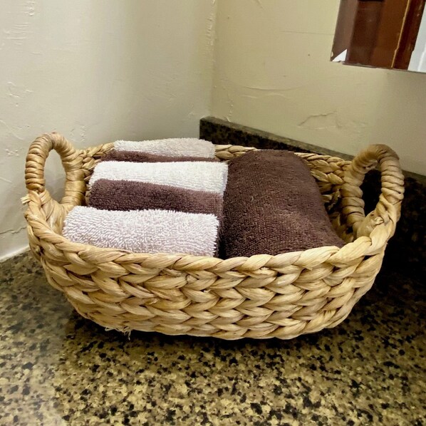 A woven basket with towels on a granite countertop.