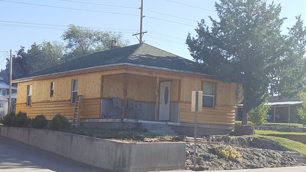 A small, single-story log cabin with a gabled roof, a front porch, and a visible door.