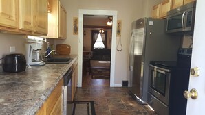 A kitchen with wooden cabinets, a stainless steel refrigerator, a microwave, and a coffee maker.