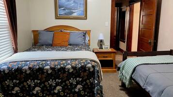A bedroom with a bed, bedside table, lamp, and a painting on the wall.