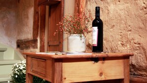 A wooden table with a bottle of wine and a vase of flowers.