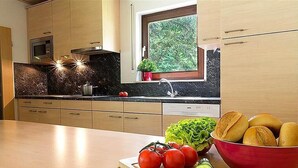 Una cocina moderna con armarios de madera, una encimera negra y un ventanal con vistas a zonas verdes.