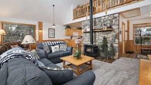 A cozy living room with a sectional sofa, a wooden coffee table, and a stone fireplace.