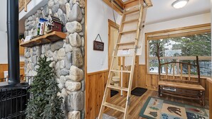 A rustic interior with a stone wall, wooden ladder, and a small Christmas tree.