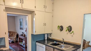 Una cocina compacta con alacenas blancas y de madera, un lavavajillas y un lavamanos.