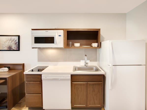 Una cocina compacta con microondas, pileta y refrigerador blanco.