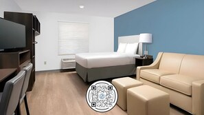 Relax in a spacious room with a large bed, beige sofa, and flat-screen TV.