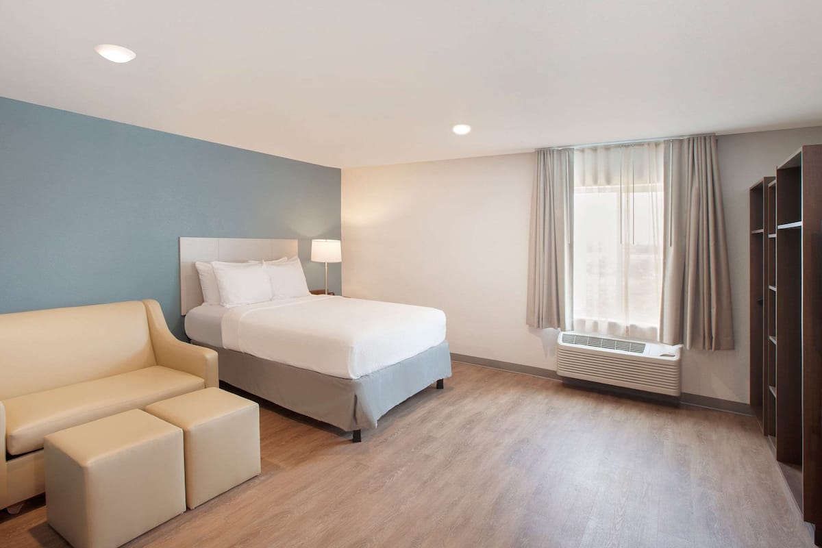 Ein Hotelzimmer mit einem Bett, einem Schlafsofa, einem Fenster mit Vorhängen, einem Heizkörper und einem Kleiderschrank.