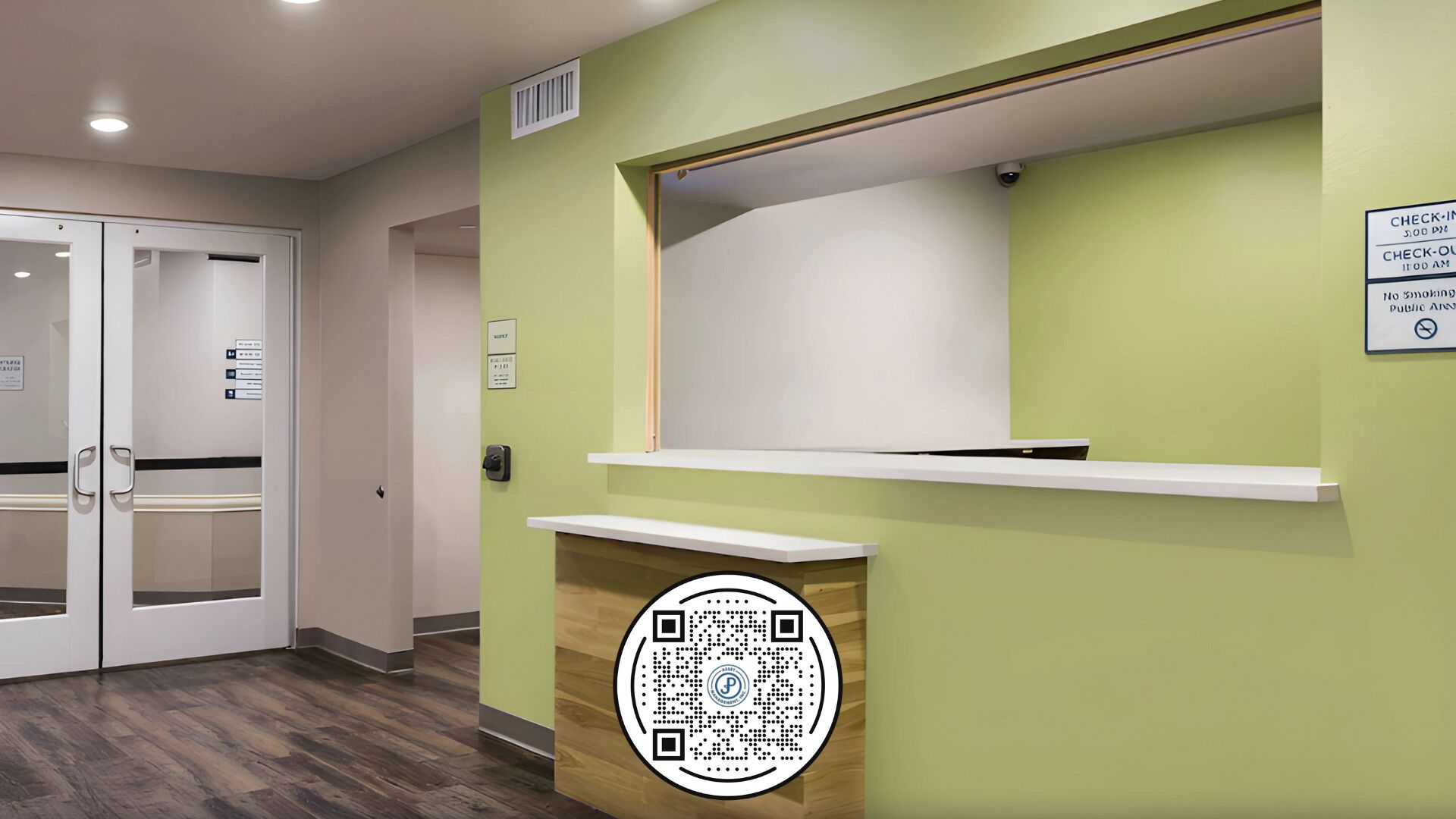 A reception area with a green wall, a white reception desk, and a QR code on the wall.