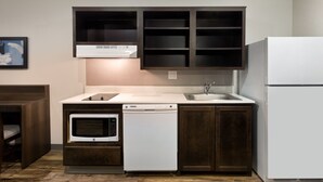 A compact kitchen with a microwave, dishwasher, and refrigerator. - WoodSpring Suites Houston 288 South Medical Center (Houston)