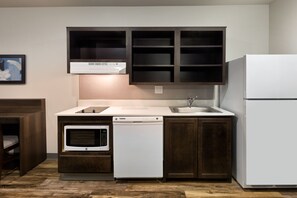 A compact kitchen with a microwave, dishwasher, and refrigerator. - WoodSpring Suites Houston 288 South Medical Center (Houston)