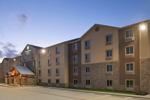 Welcome to Woodspring Suites, a multi-story hotel with a covered entrance and various room types.