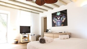 Una habitación de hotel moderna con una cama grande, un televisor de pantalla plana, techo de madera y una obra de arte colgada en la pared.
