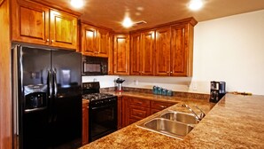 Una cocina con armarios de madera, un refrigerador negro, una estufa y un fregadero.