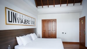 Une chambre d’hôtel avec un grand lit, une tête de lit en bois, une armoire en bois et un panneau encadré accroché au mur.