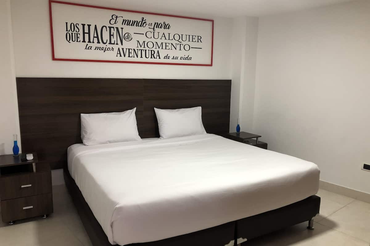 A neatly made bed with white linens, a dark headboard, and two bedside tables with lamps.