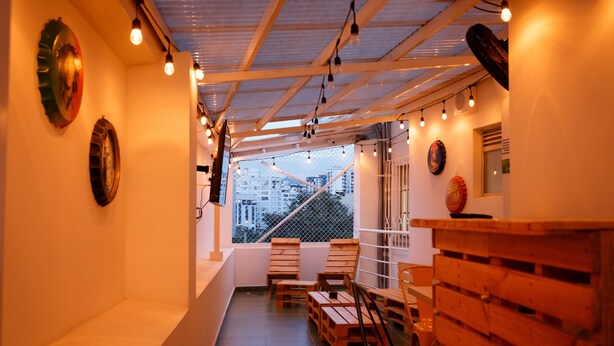 Un couloir avec des bancs et des chaises en bois, un comptoir en bois et une vue sur des immeubles par une fenêtre.