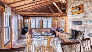 Un interior de cabaña acogedor con comedor, chimenea y estanterías.