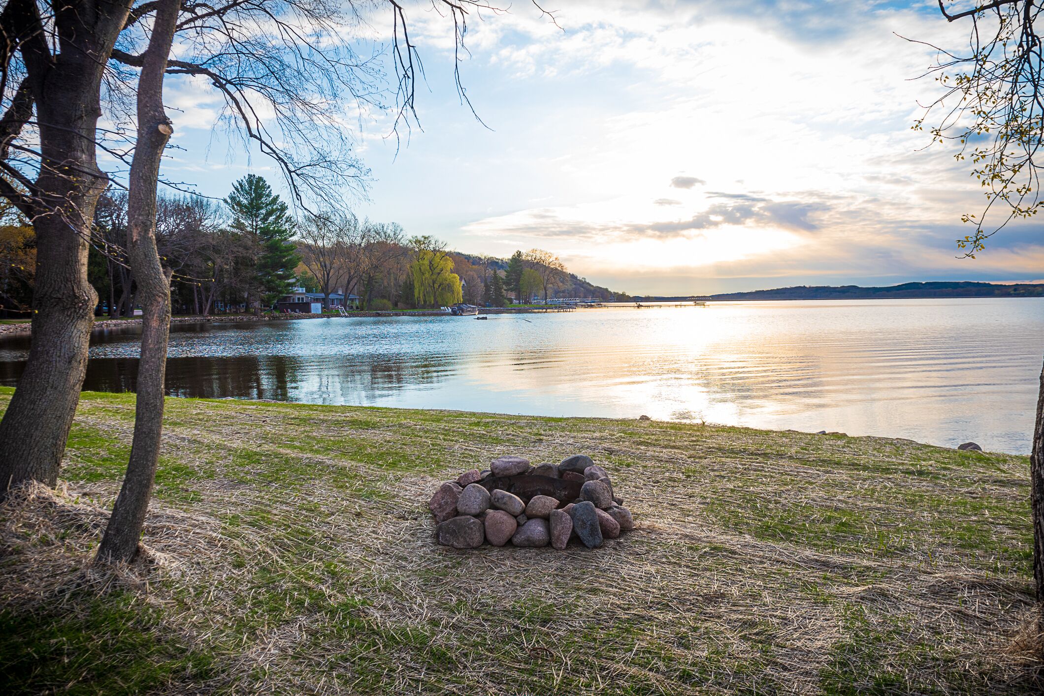 Vista de un lago con un hogar de piedra y árboles.