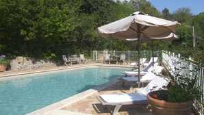 A pool area with lounge chairs and umbrellas, surrounded by greenery. - La Quercia-Erica - One Bedroom Apartment, Sleeps 5 (Val Canina)