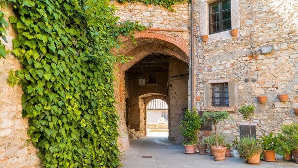 A stone building with an arched doorway, potted plants, and a window. - La Quercia-Erica - One Bedroom Apartment, Sleeps 5 (Val Canina)