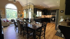 A spacious kitchen with dark cabinets, a central island, and a dining area with a wooden table and chairs.
