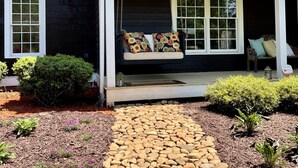 A house with a porch, a stone pathway, and a small garden.