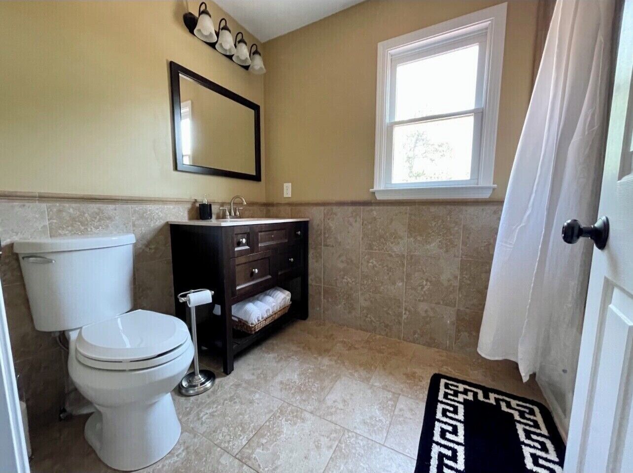 Un baño con inodoro, tocador y ventana.