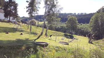 Un espace extérieur verdoyant avec des balançoires et un petit étang.