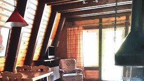 A rustic interior with a tiled floor, wooden furniture, and a large chimney.