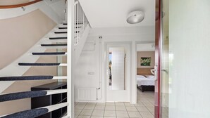 Una escalera de diseño moderno que conduce a un dormitorio con una cama y un cuadro en la pared.
